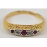 A yellow metal and platinum three stone ruby and diamond ring, size L/M, 2.1g.