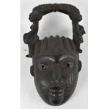 TRIBAL ART; an African carved wooden mask with rail top carved with figures, height 38cm.