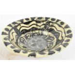 A possibly ancient earthenware bowl decorated with black designs on a cream ground, diameter 18cm.