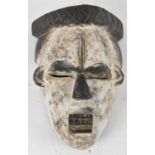 TRIBAL ART; a West African carved wooden mask with white pigmentation, height 27cm.