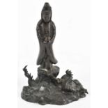 A Chinese patinated metal figure of Guanyin standing with dragons at her feet, height 19.5cm.