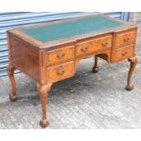 An early 20th century walnut five drawer knee-hole writing table with green leather inset top on