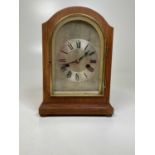 An Edwardian oak mantel clock, with arched case and silvered chapter ring with roman numerals.