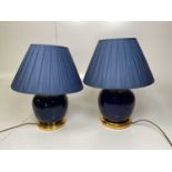 A near pair of blue glazed globular table lamps with gilt wooden bases and pleated shades, one