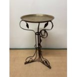 A wrought iron scrolling frame set with a brass tray top.