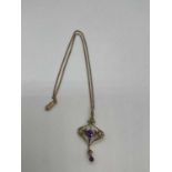 A 15ct yellow gold chain suspending an Art Nouveau seed pearl and amethyst pendant, length of