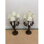 A pair of French gilt brass table lamps modelled as three branch candelabra each with mask adorned