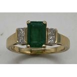 An 18ct yellow gold emerald and diamond ring, the emerald cut emerald set with four princess cut