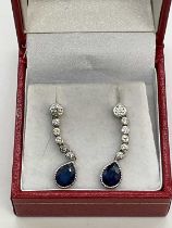A pair of 18ct white gold diamond and sapphire drop earrings, each set with a pear shaped sapphire