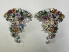 A pair of Meissen wall consoles with cherubs and encrusted with floral detail, height 18cm.