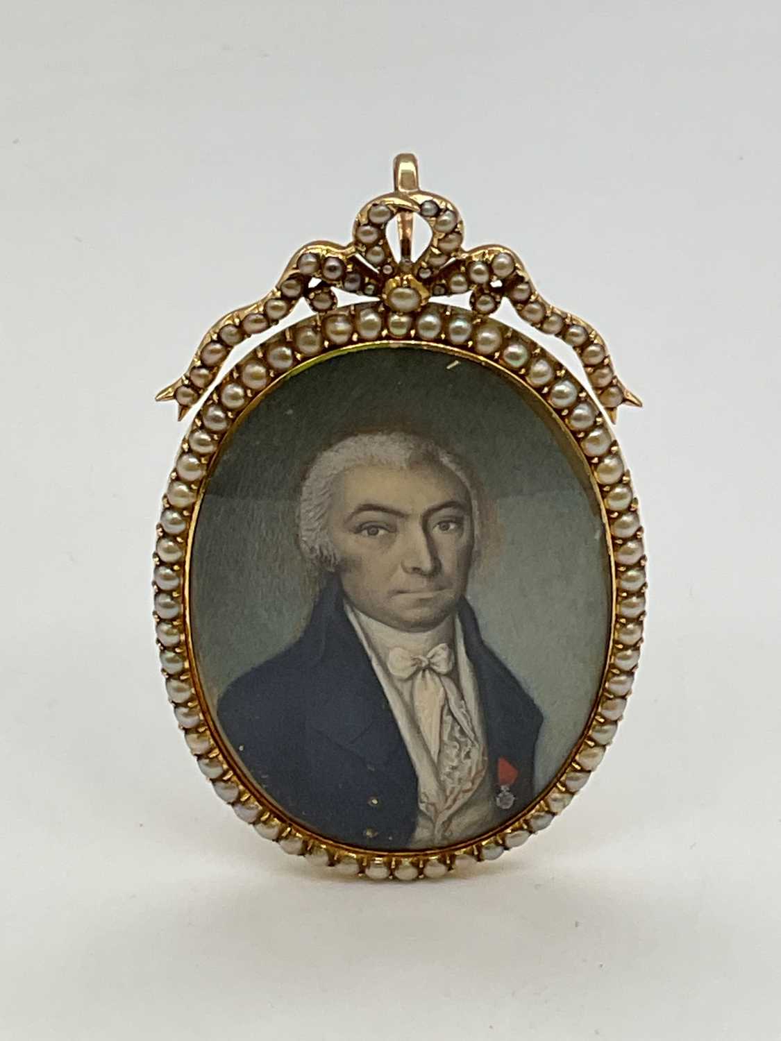 X An early 19th century oval portrait miniature set in seed pearl adorned yellow metal frame with