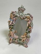 A Sitzendorf dressing table mirror decorated with cherubs on a scrolled border frame with