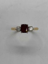 An 18ct yellow gold ruby and diamond three stone ring, the central cushion cut ruby flanked by
