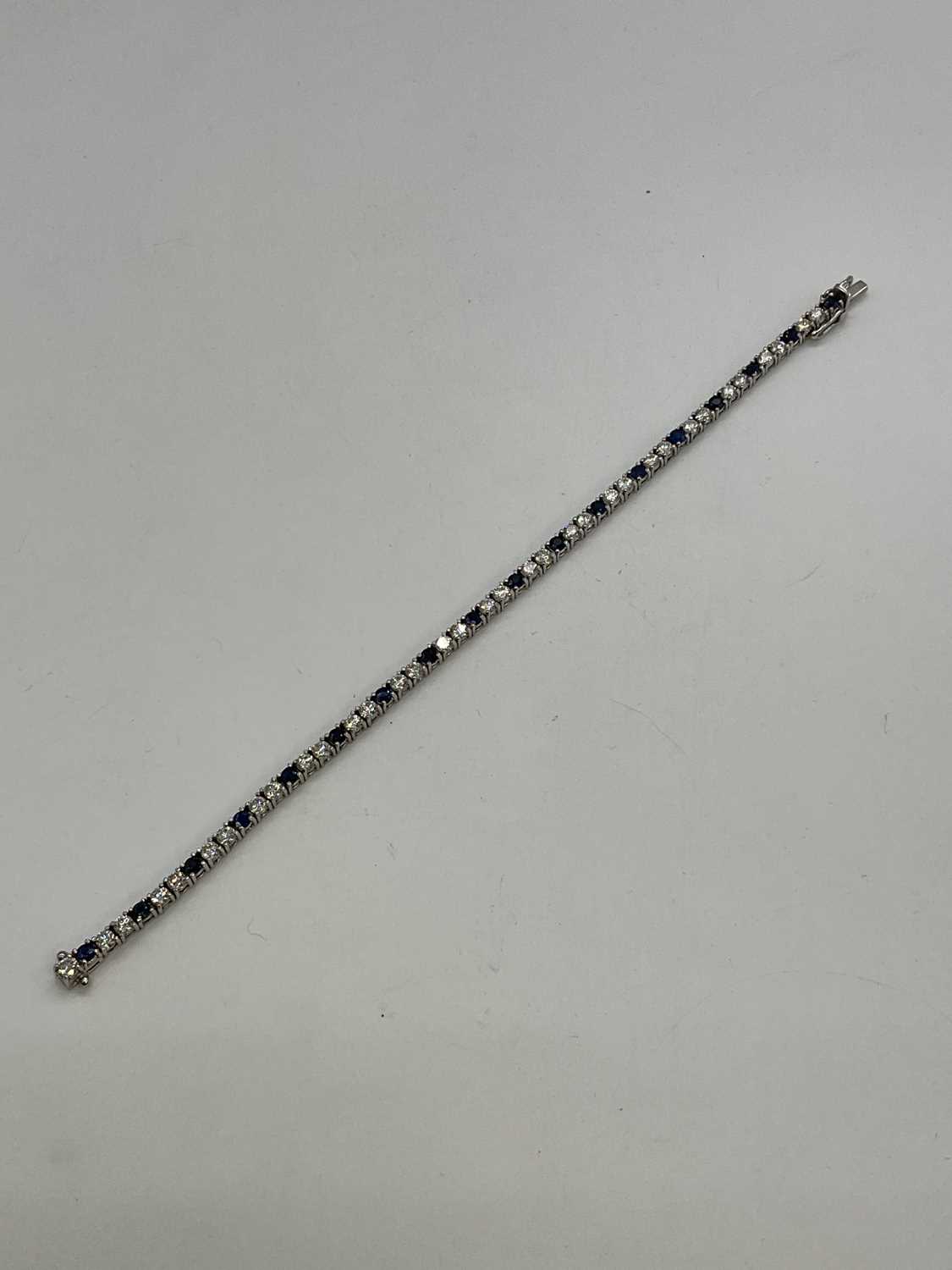 An 18ct white gold diamond and sapphire line bracelet formed of thirty-five round brilliant cut