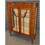 An Art Deco style walnut two door display cabinet on cabriole legs, width 87cm.