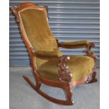 A Victorian carved mahogany framed rocking chair with serpentine seat.