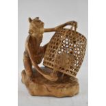 TAMORA GALLERY, BALI; a fine carved wooden scupture of an elderly man feeding a caged chicken,