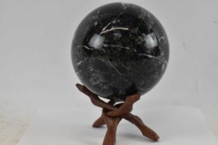 A fossiled stone orb on folding wooden base, height 20cm including stand, diameter approx 14cm.