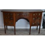 An early 19th century mahogany and boxwood strung bow fronted kneehole sideboard on turned fluted