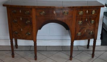 An early 19th century mahogany and boxwood strung bow fronted kneehole sideboard on turned fluted