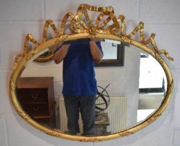 A late 19th century decorative gilt oval wall mirror with ribbon surmount and bevelled plate, 67 x