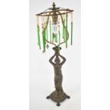 A late 19th century patinated spelter figural lamp with skeleton shade suspending several glass