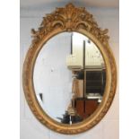 A large late 19th century ornate oval gilt framed wall mirror, approx. 105 x 80cm.