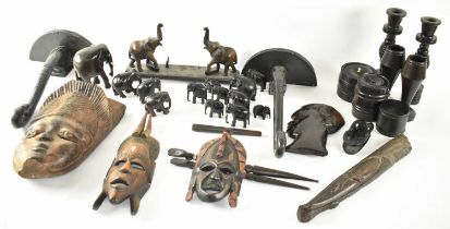 A large group of African tribal style tourist carvings, to include masks, candlesticks, lidded jars,