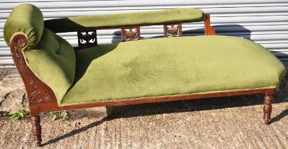 An early 20th century mahogany chaise longue with carved detail and green upholstery.