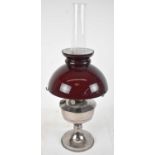 A 20th century silver plated oil lamp, with cranberry glass shade, height to top of chimney
