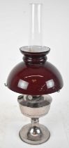 A 20th century silver plated oil lamp, with cranberry glass shade, height to top of chimney