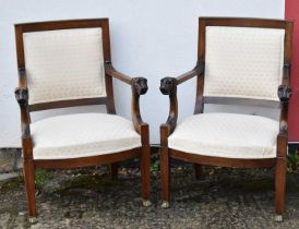 A pair of mahogany open arm elbow chairs with lion head carvings to the arms, on square tapering