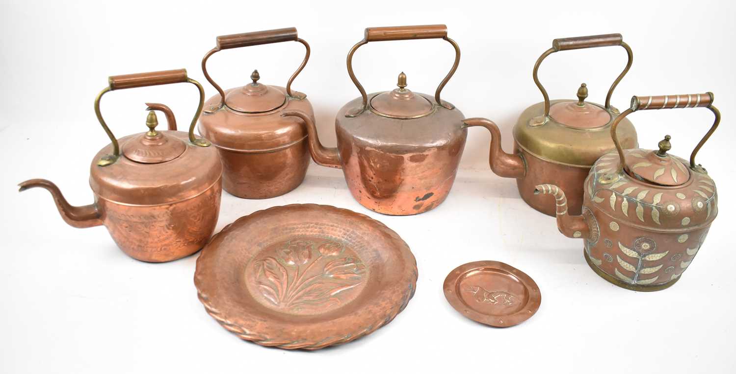 A group of five copper kettles, an Art Nouveau style copper wall hanging plaque and another copper