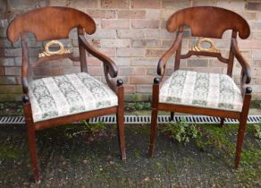 A pair of Empire Revival elbow chairs with padded seats and sabre front legs.