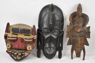 A carved tribal mask with polychrome decoration and two further tribal masks (3).