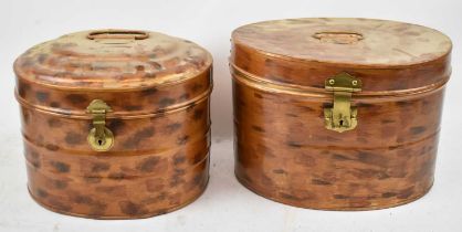 Two copper effect oval hat tins with brass locks, width 38cm and 35cm respectively.