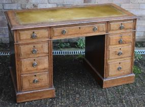 An early 20th century oak twin pedestal nine drawer desk with leather inset top, width 121cm.