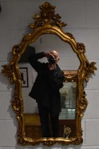 A contemporary gilt framed wall mirror with floral detail, height 103cm.