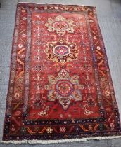 A large Persian red ground floral decorated carpet, 144 x 235cm.