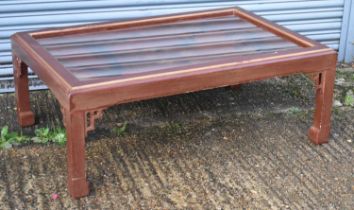 A modern Chinese style red lacquer coffee table with glass top above painted decoration, 130 x