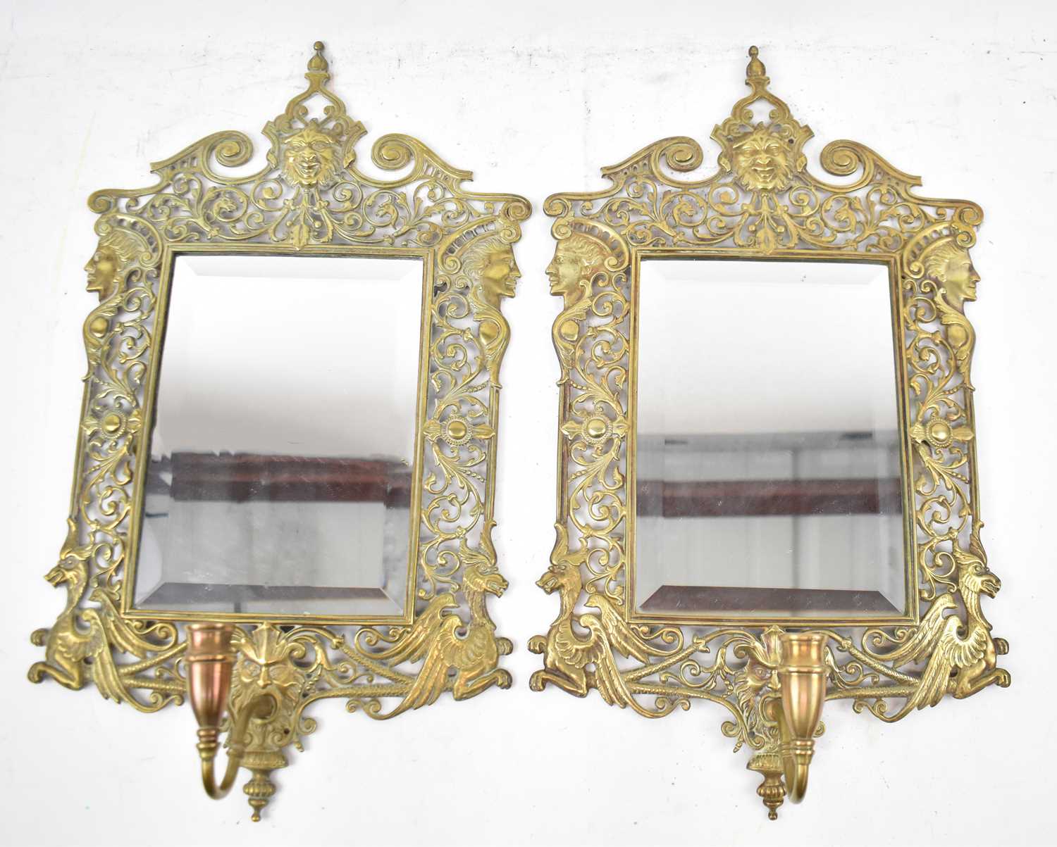 A pair of decorative pierced brass bevelled wall mirrors with single candle sconces, height 51 x