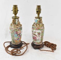 A pair of late 19th century Chinese Canton Famille Rose porcelain table lamps, on carved hardwood