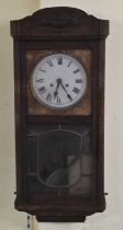 A 1920s oak wall clock, the white painted dial set with Roman numerals, height approx 82cm.
