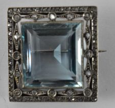 A white metal brooch set with central aquamarine, 2.5 x 2.5cm.