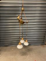 An early 20th century brass ceiling light, with four white glass shades, approx height 115cm.