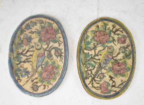 A pair of 18th/19th century Persian oval tiles, each painted with a bird amongst floral sprays, 27.5