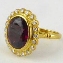 An 18ct gold diamond and garnet ring, the bezel set cut oval garnet length 11.5mm, width 9.3mm,