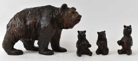 A carved Black Forest bear, length 26cm, height 17cm, with three assorted cubs (4).