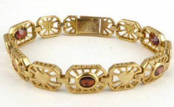 A 9ct gold bracelet with eleven open oval panels with alternating heart and bezel set oval