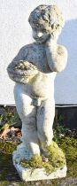 An early 20th century composite stone garden figure of a young boy holding a basket of fruit, height